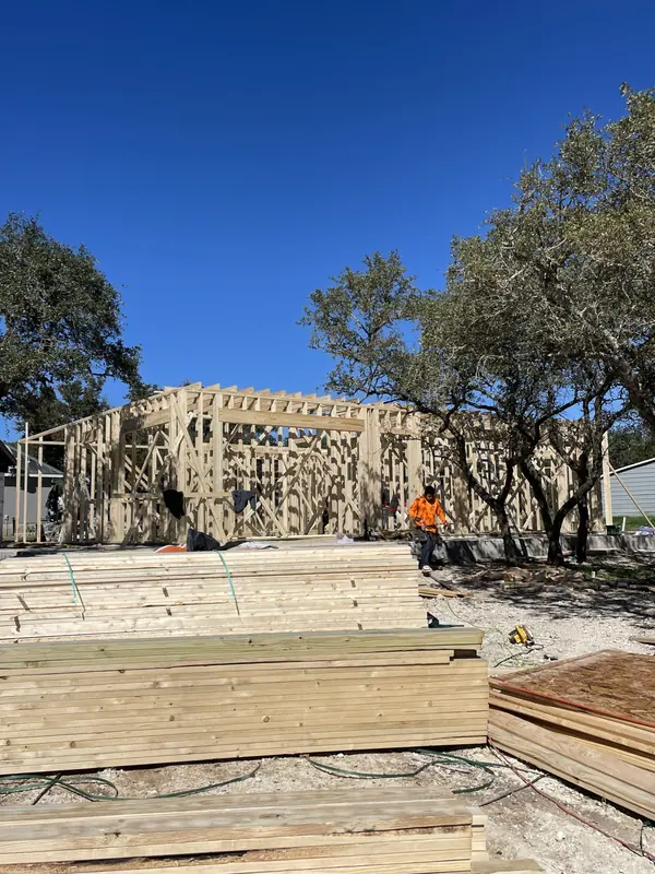 Residential framing on a wooded lot with stacked lumber on site