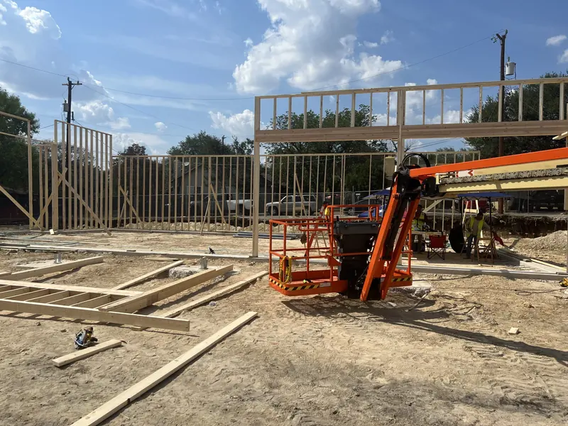 Framing crew using a boom lift to set upper level structure