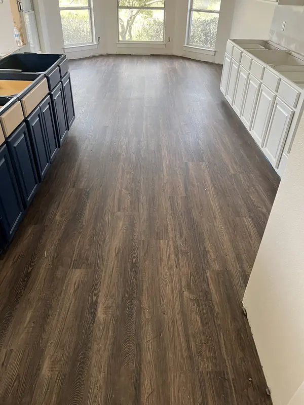 Dark hardwood flooring through an open kitchen and dining area with navy and white cabinetry