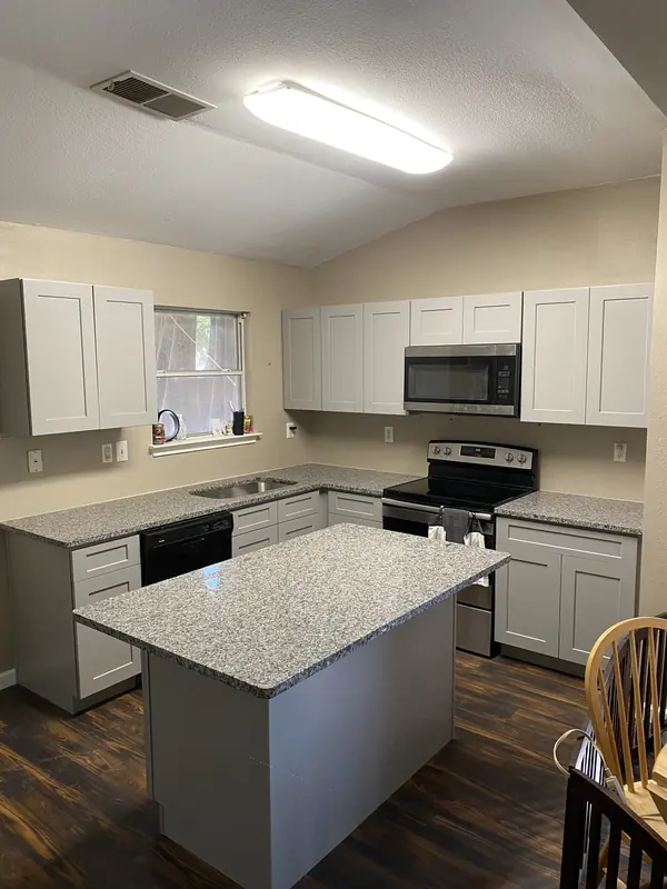 Remodeled kitchen with white cabinets, granite island and dark hardwood flooring