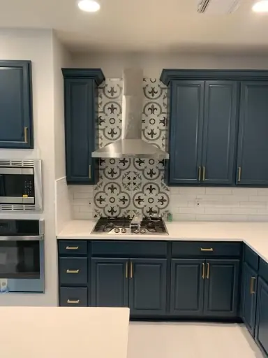 Navy kitchen cabinets with patterned tile backsplash and stainless range