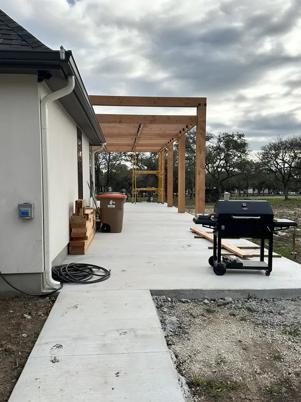 Covered patio structure with cedar beams alongside a new concrete slab