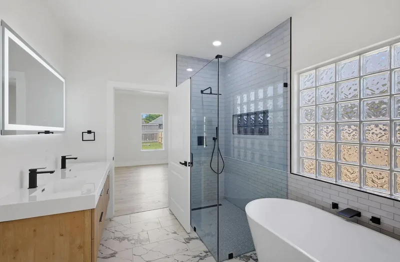 Remodeled bathroom with a freestanding tub, walk in glass shower and a glass block window