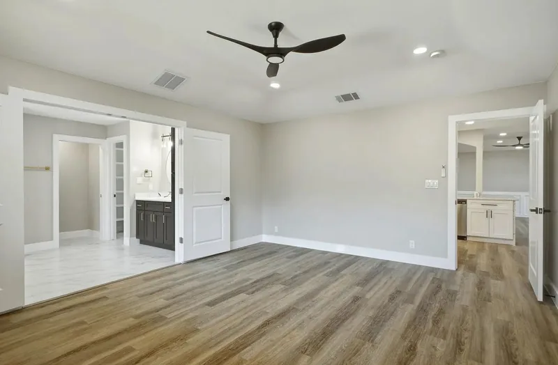 Luxury vinyl plank flooring in an empty bedroom, meeting tile at the ensuite doorway