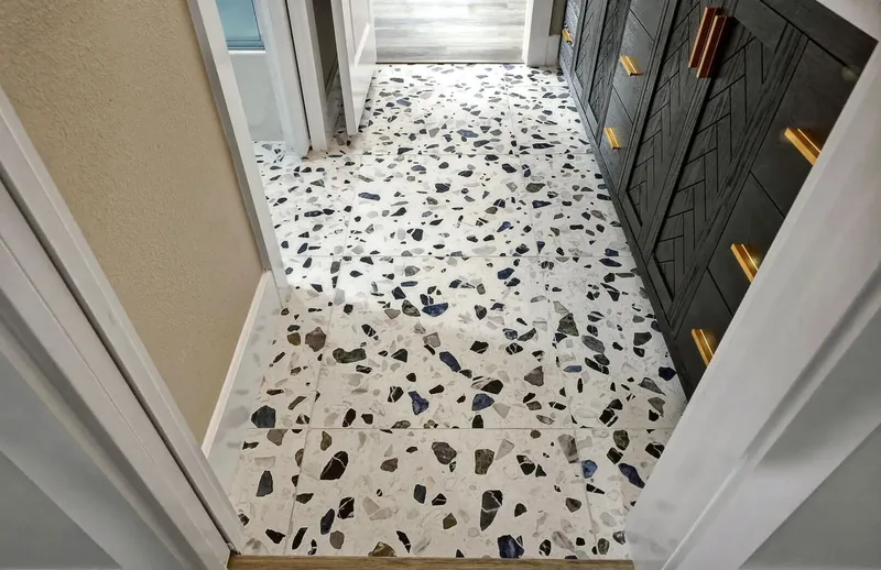Terrazzo tile floor laid through a hallway beside a dark panelled door