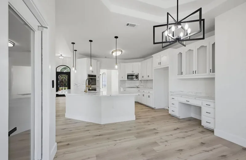 Open kitchen with white cabinets, a marble effect island and a black framed chandelier