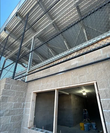 Commercial chain link mesh panels fixed between steel posts along a block wall under a grandstand